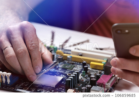 A technician repairs a motherboard in a service center. Computer Repair 106859685