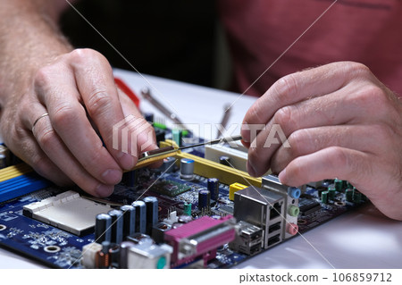 A technician repairs a motherboard in a service center. Computer Repair 106859712