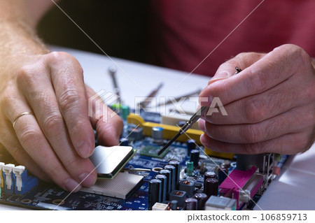 A technician repairs a motherboard in a service center. Computer Repair 106859713