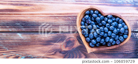 Freshly picked blueberries in a heart-shaped wooden plate on a wooden table, top view Freshly picked blueberries in a heart-shaped wooden plate on a wooden table, top view 106859729