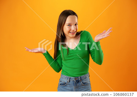 Puzzled teen girl don't know what to do on yellow background in studio Puzzled teen girl don't know what to do on yellow background in studio 106860137