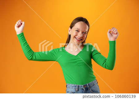 Portrait of a joyful happy teenage girl celebrating success on yellow background 106860139