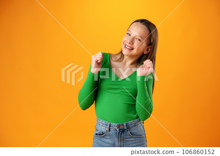 Portrait of a joyful happy teenage girl celebrating success on yellow background Portrait of a joyful happy teenage girl celebrating success on yellow background 106860152