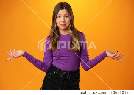 Puzzled teen girl don't know what to do on yellow background in studio Puzzled teen girl don't know what to do on yellow background in studio 106860154