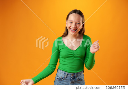 Portrait of a joyful happy teenage girl celebrating success on yellow background Portrait of a joyful happy teenage girl celebrating success on yellow background 106860155