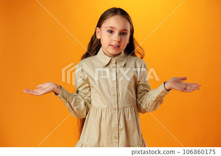 Teen girl shows I don't know gesture against yellow background Teen girl shows I don't know gesture against yellow background 106860175