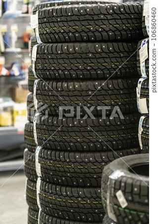 Sale of car tires for sale in the store. Many new winter tires lie horizontally. There is space for text Sale of car tires for sale in the store. Many new winter tires lie horizontally. There is space for text 106860460