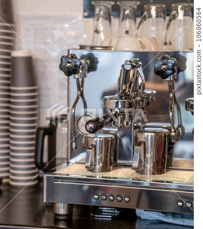 The barista prepares fresh coffee in the coffee machine in the morning in the cafe. There are coffee cups on the table for customers. Coffee machine close-up The barista prepares fresh coffee in the coffee machine in the morning in the cafe. There are coffee cups on the table for customers. Coffee machine close-up 106860564