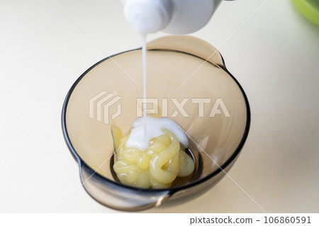 girl in blue rubber protective gloves holding a brush in her hands and stirring hair dye close-up colorist hair care at home hair mask. girl in blue rubber protective gloves holding a brush in her hands and stirring hair dye close-up colorist hair care at home hair mask. 106860591