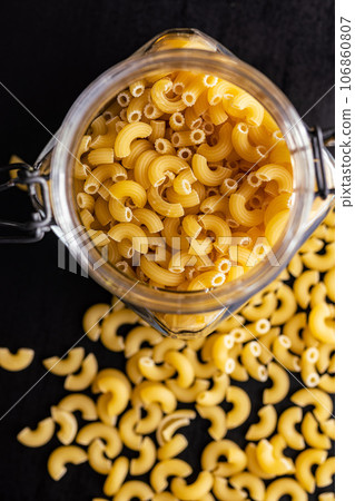 Raw macaroni pasta in glass bottle. Uncooked rigatoni in jar. Raw macaroni pasta in glass bottle. Uncooked rigatoni in jar. 106860807