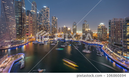 Dubai marina tallest skyscrapers and yachts in harbor aerial day to night timelapse. 106860894