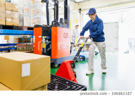 A female worker using a hand lift in a warehouse A female worker using a hand lift in a warehouse 106862187