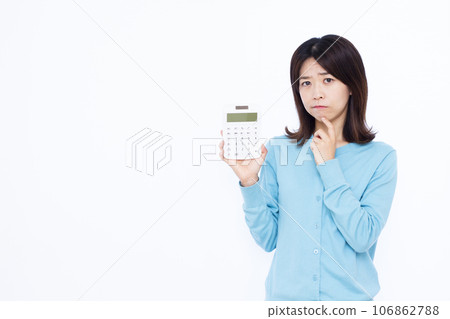 一位 30 多歲的家庭主婦拿著計算器，在白色背景前擔心 106862788