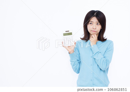 A housewife in her 30s holding a calculator and worrying in front of a white background A housewife in her 30s holding a calculator and worrying in front of a white background 106862851