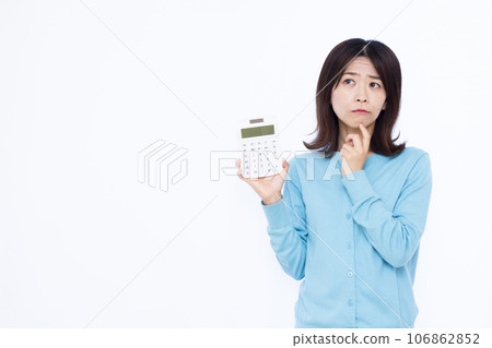 一位 30 多歲的家庭主婦拿著計算器，在白色背景前擔心 106862852
