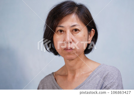 一位中年婦女,臉上有斑點和皺紋,看著鏡頭 一位中年婦女,臉上有斑點和皺紋,看著鏡頭 106863427