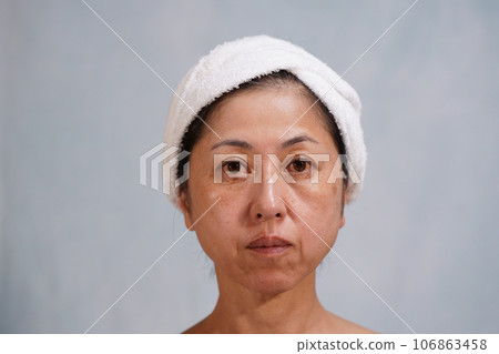 一位中年婦女，臉上有斑點和皺紋，看著鏡頭 106863458