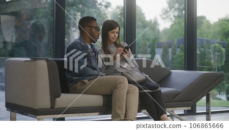 Multiethnic couple sits on sofa in clinic lobby area Multiethnic couple sits on sofa in clinic lobby area 106865666