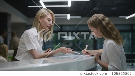 Female administrator consults person, helps fill out papers in hospital 106865802