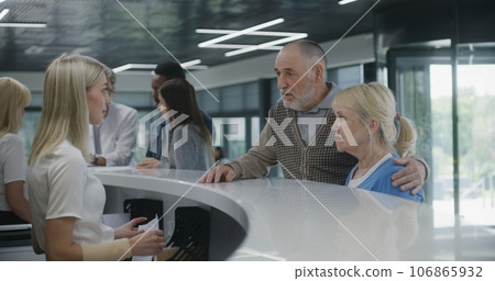 Elderly couple stand near reception desk in clinic 106865932