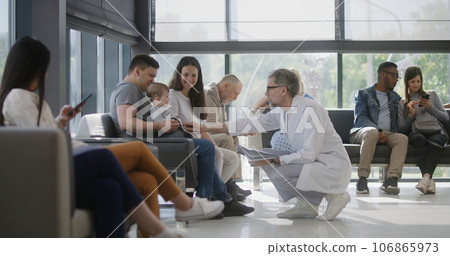 Doctor talks to family with little child in clinic waiting room 106865973