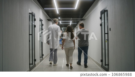 Doctor and family with child walk the clinic corridor 106865988