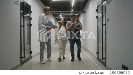 Mature doctor and family discuss treatment in clinic corridor 106866023