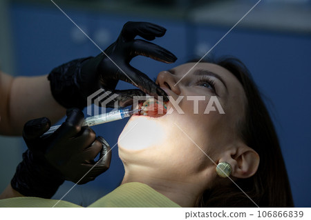 The process of removing braces.Beautiful woman in dental chair during procedure of installing braces to upper and lower teeth. Dentist and assistant working together, dental tools in their hands.  106866839