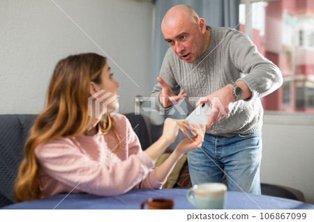 Amazed woman trying to don't give away her phone to her jealous husband Amazed woman trying to don't give away her phone to her jealous husband 106867099