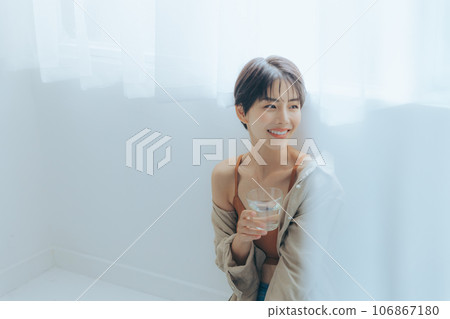 A woman relaxing by the window with a cup in hand A woman relaxing by the window with a cup in hand 106867180