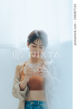A woman relaxing by the window with a cup in hand A woman relaxing by the window with a cup in hand 106867181