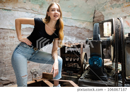 Young woman standing near old machine tool in destroyed plant Young woman standing near old machine tool in destroyed plant 106867187