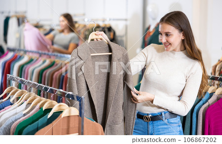 Customer deciding on demi-season coat in women cloths shop Customer deciding on demi-season coat in women cloths shop 106867202
