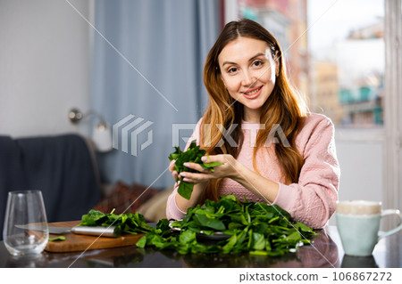 Happy girl making delicious spinach salad closeup Happy girl making delicious spinach salad closeup 106867272