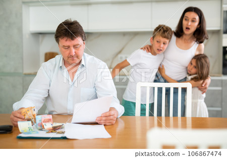 Thoughtful father counting money looking through papers in the kitchen Thoughtful father counting money looking through papers in the kitchen 106867474