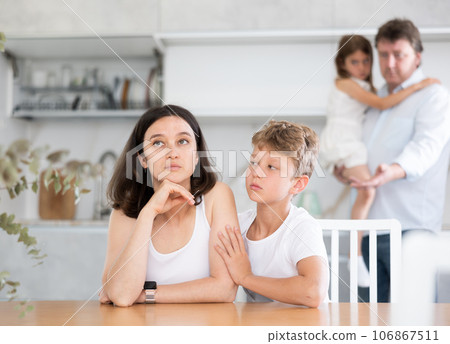 Son soothe his mother after a domestic quarrel. Father with little daughter in background Son soothe his mother after a domestic quarrel. Father with little daughter in background 106867511