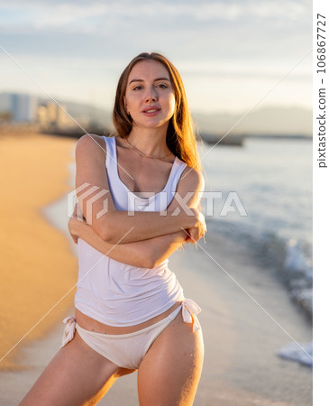 Beautiful woman with blond hair in elegant bikini posing on sunset beach Beautiful woman with blond hair in elegant bikini posing on sunset beach 106867727