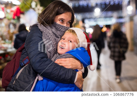 Preteen boy with mother having fun at Christmas street market Preteen boy with mother having fun at Christmas street market 106867776