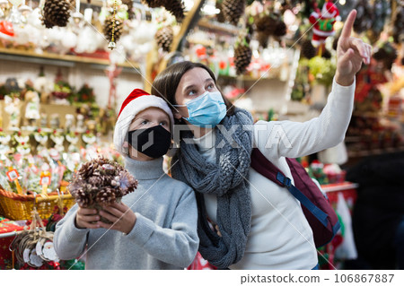 Tween boy with mother in protective masks on Christmas street market Tween boy with mother in protective masks on Christmas street market 106867887