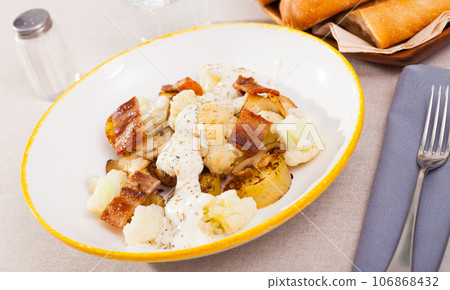 Baked potatoes with cauliflower, bacon, cheese sauce 106868432