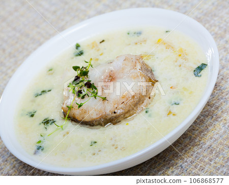 Boiled creamy soup with white fish pollock and greens at plate Boiled creamy soup with white fish pollock and greens at plate 106868577