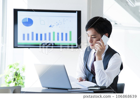 A young businessman working on a smartphone and computer in the office A young businessman working on a smartphone and computer in the office 106868639