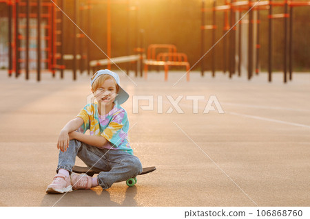A child or girl skater sits on a skateboard. 106868760