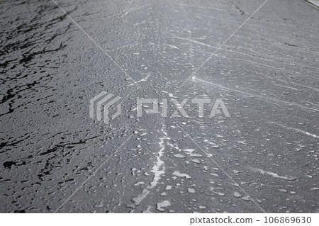 Rain falling on a paved road and flowing neatly towards the gutters 106869630