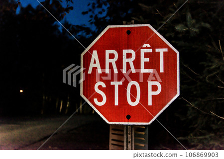 Security stop slow down sign at night in Canada Quebec, arret means stop in french Security stop slow down sign at night in Canada Quebec, arret means stop in french 106869903