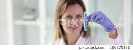 Female scientist looks at test tube with liquid in her hand. 106870328