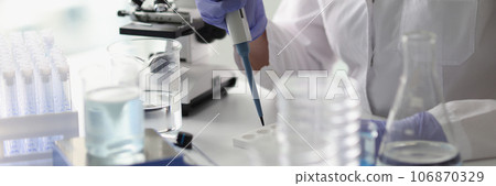 Professional woman scientist with pipette in her hand is working in scientific laboratory. 106870329