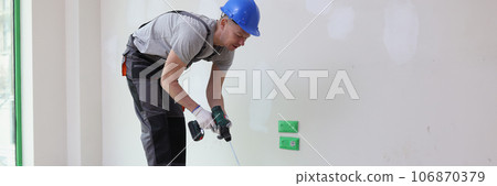 Male decorator mixes paint in bucket with mixer. Male decorator mixes paint in bucket with mixer. 106870379