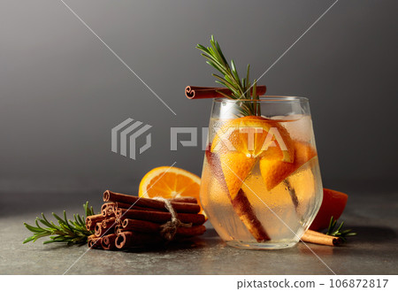 Cocktail gin tonic with ice, rosemary, cinnamon, and orange on a stone table. 106872817