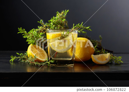 Cocktail Gin-tonic with ice, lemon, and juniper on a black background. 106872822